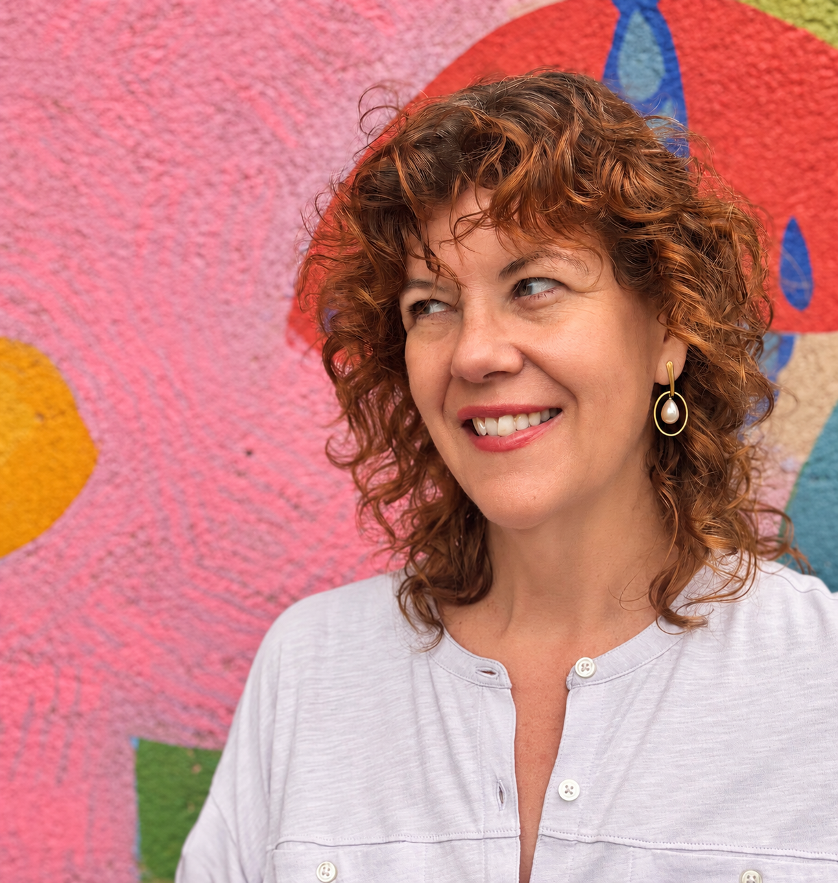 Elizabeth Bunnell smiling in front of a colorful mural